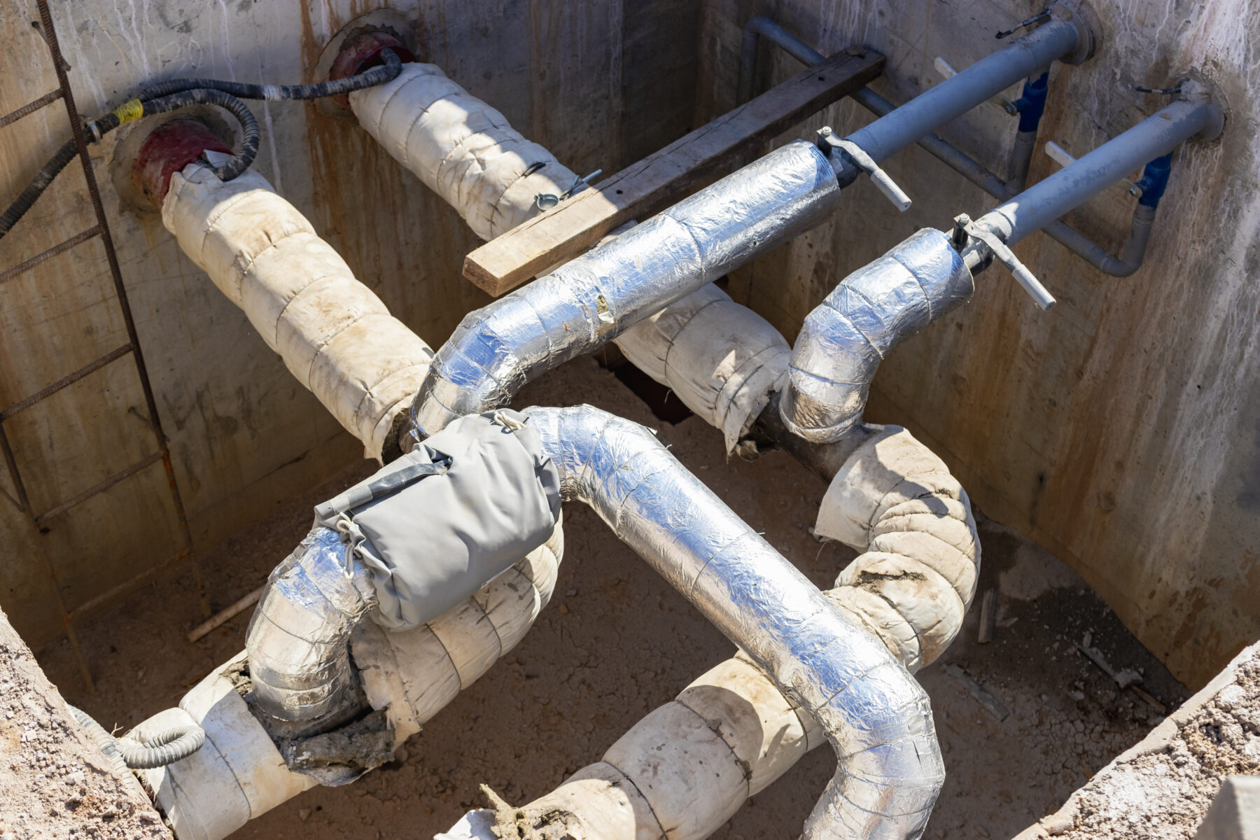 Laying of underground pipes in concrete chamber. Installation of water main at the construction site. Construction of stormwater pits, sewerage valve, sanitary system and pump station. rørisolering